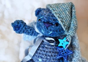 Blue teddy bear with nightcap and blanket