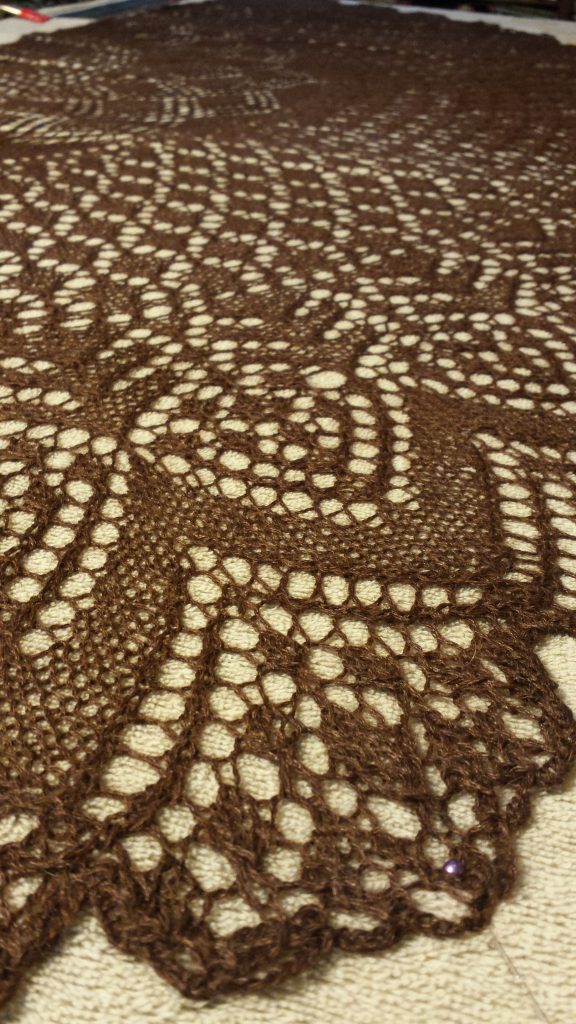 closeup detail photo of lace shawl knitted in dark brown alpaca and silk laceweight yarn.