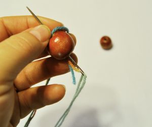 Beginning to wrap yarn through the wood bead