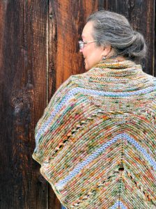 The pattern designer wearing the Bonfire Poncho shown from the rear with her face turned to the left